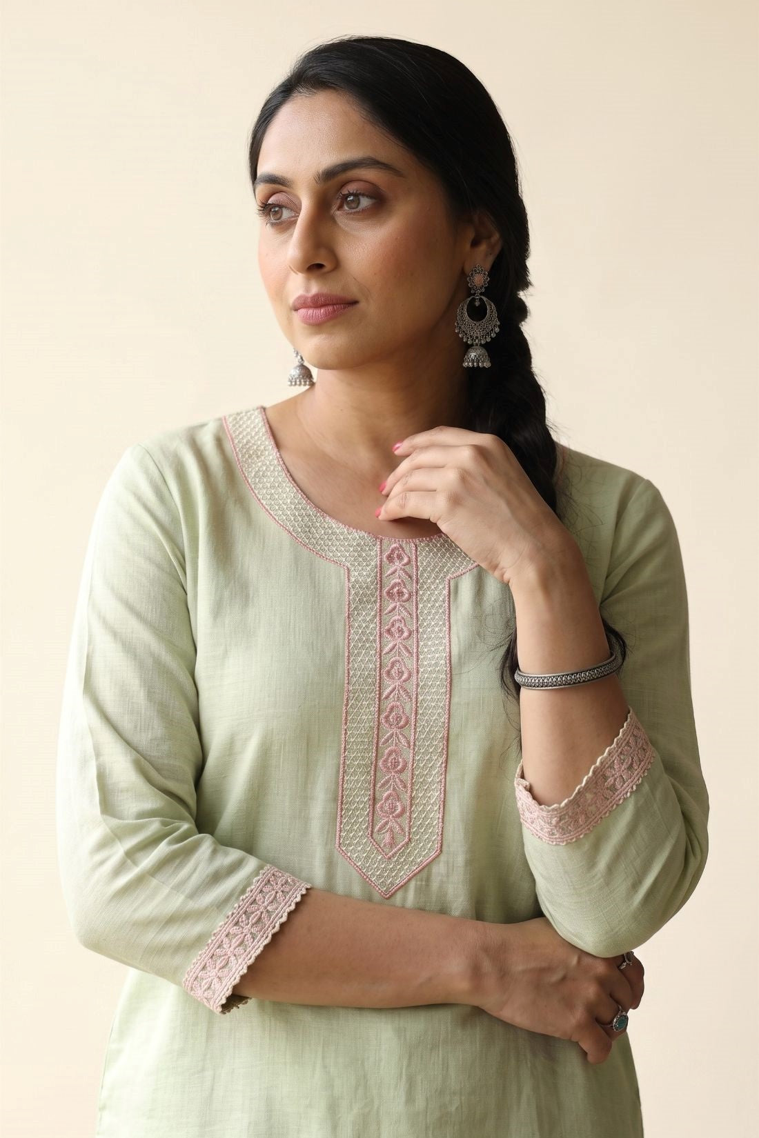 Close-up shot of a light green straight-fit kurta highlighting elegant pastel pink floral embroidery along the rounded keyhole neckline panel and matching embroidered lace borders on the three-quarter sleeves.