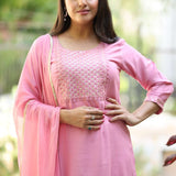 Close up shot of the delicate white thread embroidery, lace trims, and pintucks detailing on the neckline of a light pink cotton kurta