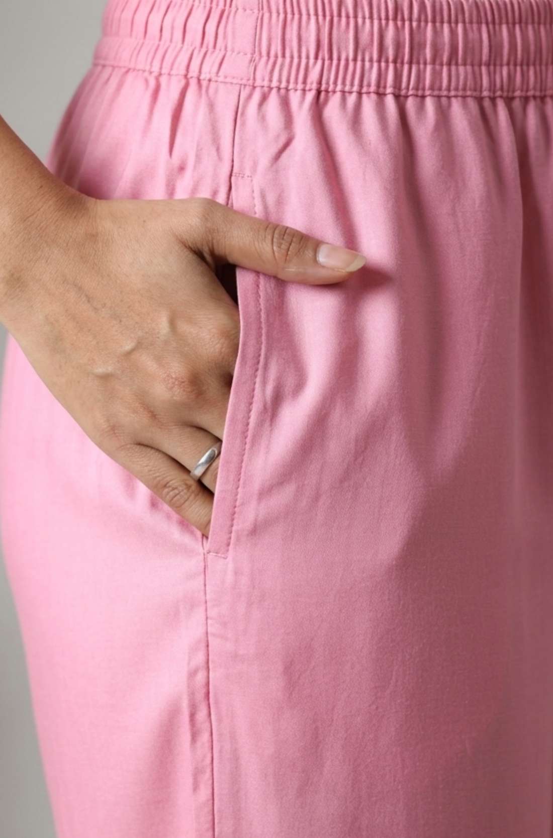 Close up view highlighting the convenient functional side utility pocket tailored into the matching straight trousers of a light pink embroidered cotton kurta set, showing a hand resting inside the pocket.