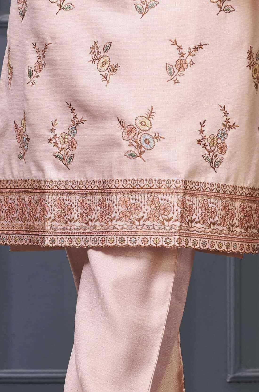 Close-up of floral embroidery and decorative scalloped border on a light pink silk blend kurta for women.