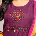 Close-up of multicolour geometric cross stitch embroidery, mirror accents and decorative tassels on magenta cotton kurta.