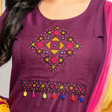 Close-up of multicolour geometric cross stitch embroidery, mirror accents and decorative tassels on magenta cotton kurta.