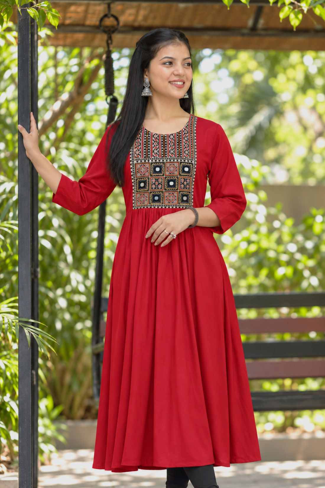 A model wearing a full-length maroon rayon A-line kurta featuring 3/4 sleeves and a geometric embroidered yoke