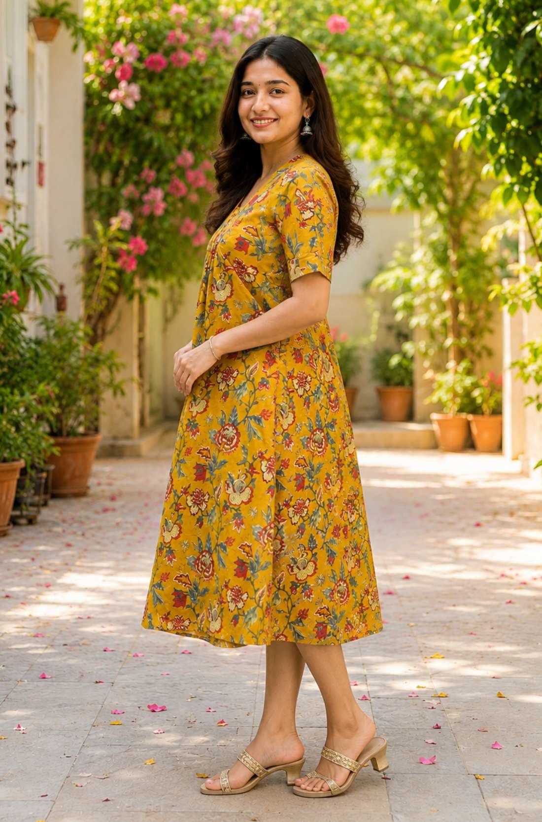 Side profile view of a woman wearing an mustard yellow cotton floral print frock-style kurti dress, showcasing the relaxed-fit elbow sleeves and A-line drape.