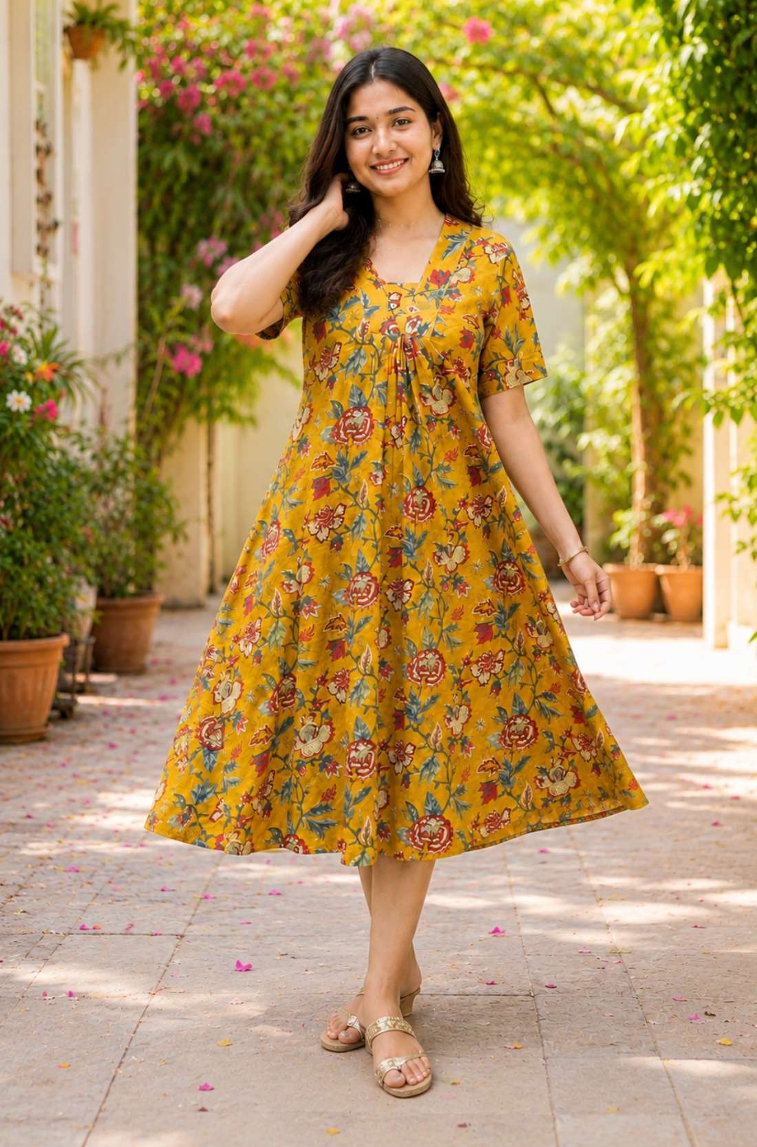 A woman posing gracefully in an mustard yellow pure cotton floral printed frock-style kurti dress, capturing the flowy movement of the flared hemline.