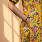 Close-up of side pocket detail on mustard yellow floral cotton midi dress.