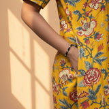 Close-up of side pocket detail on mustard yellow floral cotton midi dress.