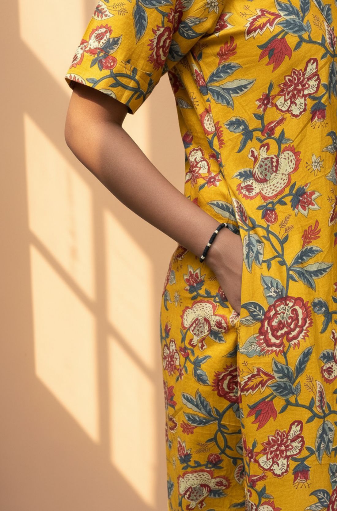 Close-up of side pocket detail on mustard yellow floral cotton midi dress.