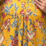 Close-up of V neckline and pleated front on mustard yellow floral cotton midi dress.