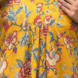 Close-up of V neckline and pleated front on mustard yellow floral cotton midi dress.