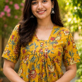 Detailed close-up of the front bodice highlighting the overlapping V-neckline cut and centered pleat gathering on an mustard yellow floral printed cotton kurti dress.