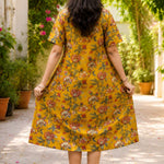 Full back view of the mustard yellow printed cotton frock kurti dress, emphasizing its flowy silhouette and continuous vibrant floral print pattern.