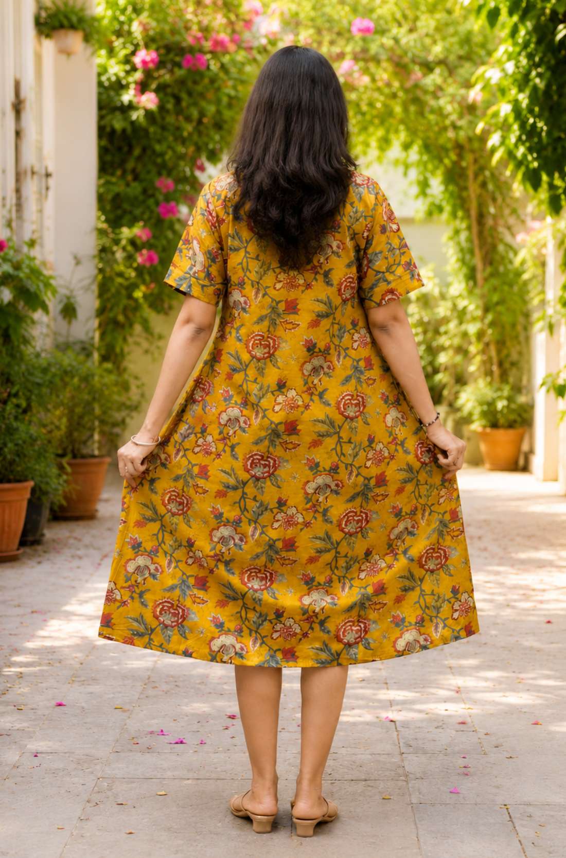 Full back view of the mustard yellow printed cotton frock kurti dress, emphasizing its flowy silhouette and continuous vibrant floral print pattern.
