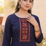 Close-up portrait of a woman wearing a navy blue straight kurta with intricate red and orange ethnic embroidery on the neckline.