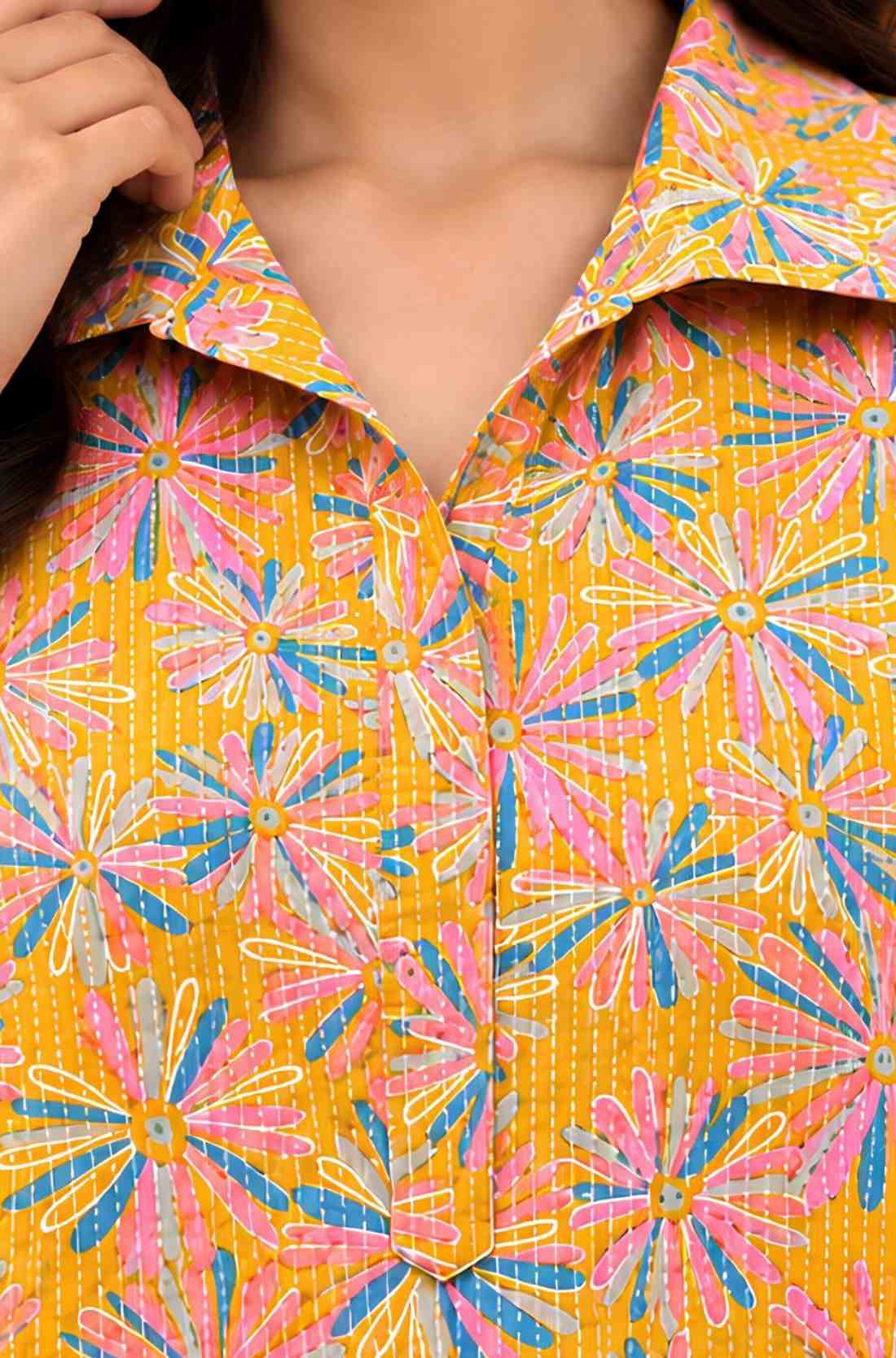 Close-up of ochre yellow cotton midi dress showing the shirt collar, V-shaped opening, front placket and pink blue floral print.