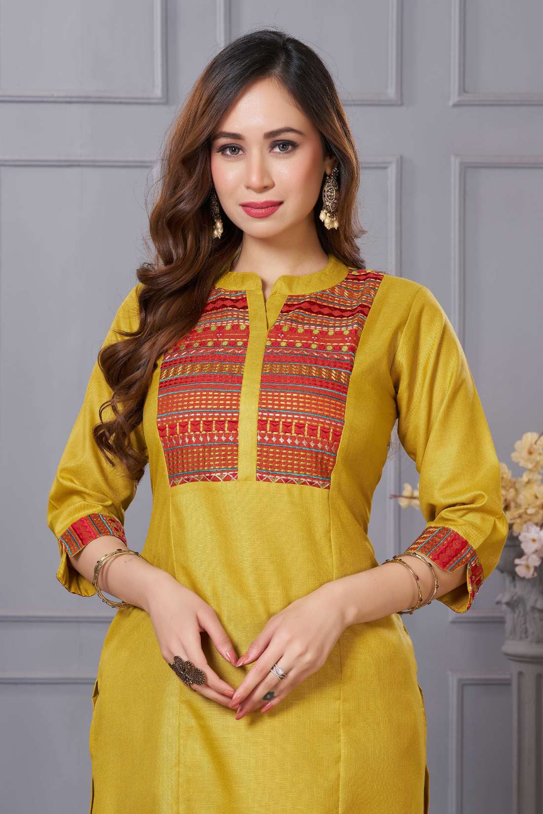 Close up detail of the intricate thread embroidery on the contrast neck yoke of the ochre yellow cotton straight kurta
