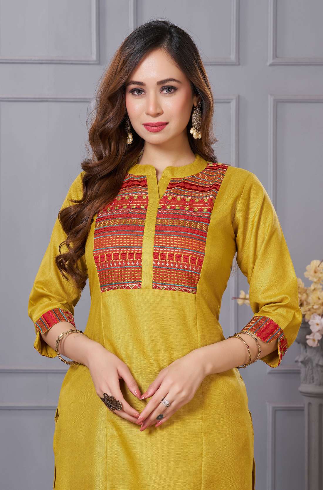 Close up detail of the intricate thread embroidery on the contrast neck yoke of the ochre yellow cotton straight kurta