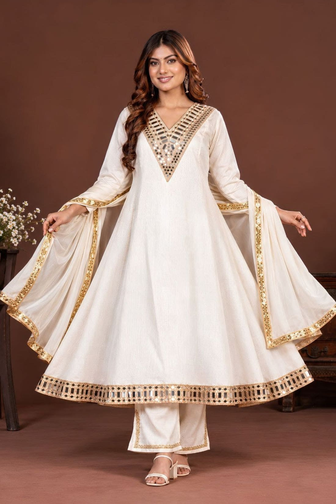 Woman wearing an off-white mirror work Anarkali kurta set with pants and dupatta