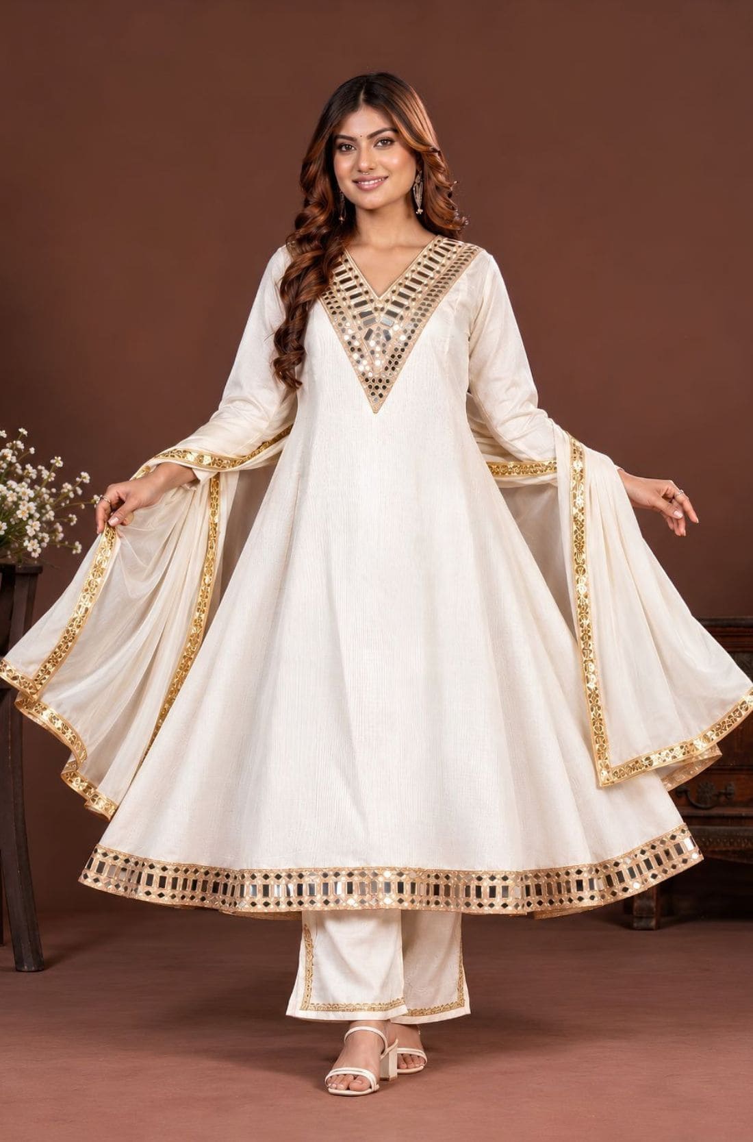 Woman wearing an off-white mirror work Anarkali kurta set with pants and dupatta