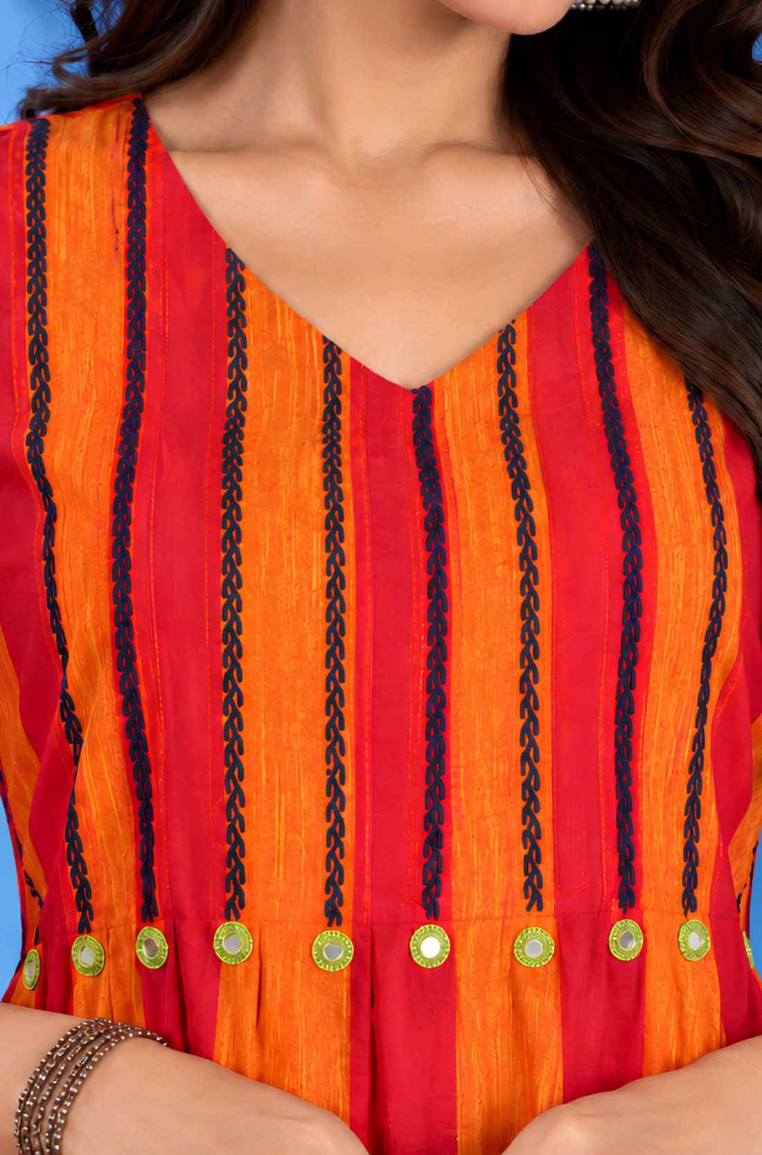 Macro shot of the V-neck and pleated yoke featuring contrast thread embroidery and mirror work accents on the orange handloom cotton midi dress for women.