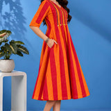 Side profile of a model showcasing the convenient pocket and elegant drape of the orange handloom cotton pintuck midi dress.