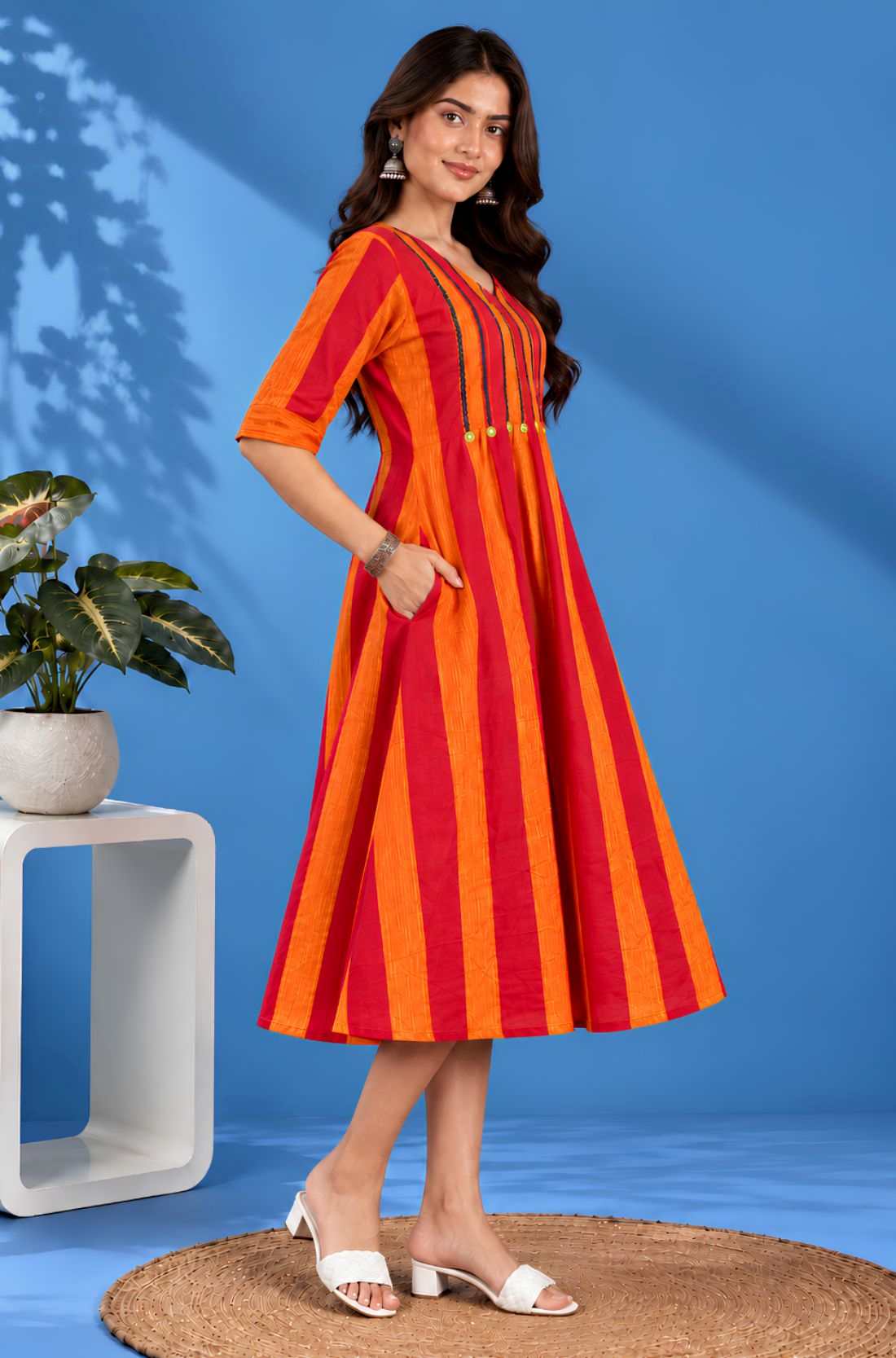 Side profile of a model showcasing the convenient pocket and elegant drape of the orange handloom cotton pintuck midi dress.