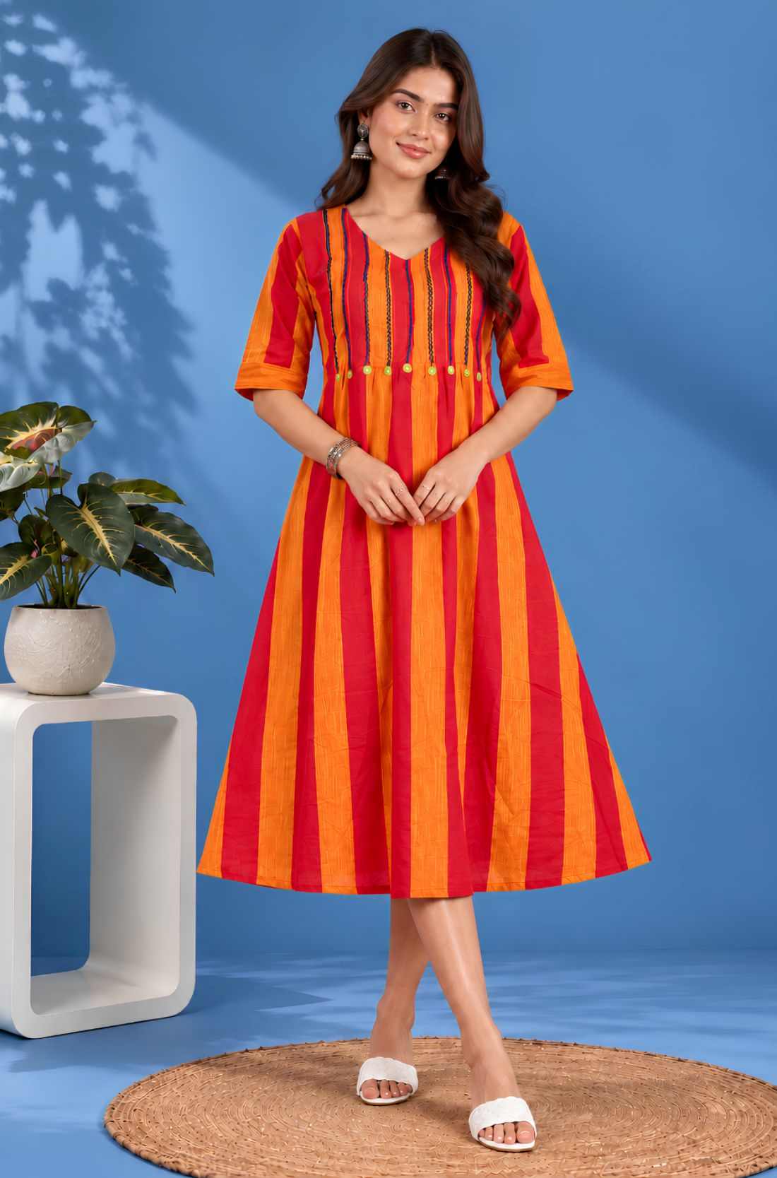 Full front view of a woman wearing an orange handloom cotton pintuck embroidered midi dress with elbow sleeves and striped pattern.