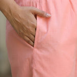 Close up view highlighting the convenient functional side utility pocket tailored into the matching straight trousers of a peach embroidered cotton kurta set, showing a hand resting inside the pocket.