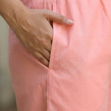 Close up view highlighting the convenient functional side utility pocket tailored into the matching straight trousers of a peach embroidered cotton kurta set, showing a hand resting inside the pocket.
