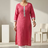 A full-length view of a woman walking gracefully while wearing a pink textured kurta and white palazzo pants.
