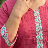 A close-up shot of the pink kurta neckline and sleeves, featuring intricate floral thread embroidery.