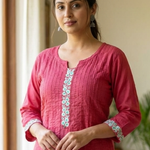 A portrait of a woman wearing a pink embroidered kurta, showcasing the elegant fit and fabric texture.