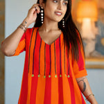 Close-up front view of the orange handloom cotton tunic featuring vertical black embroidery stitch work and yellow accent button detailing on the V-neck yoke.