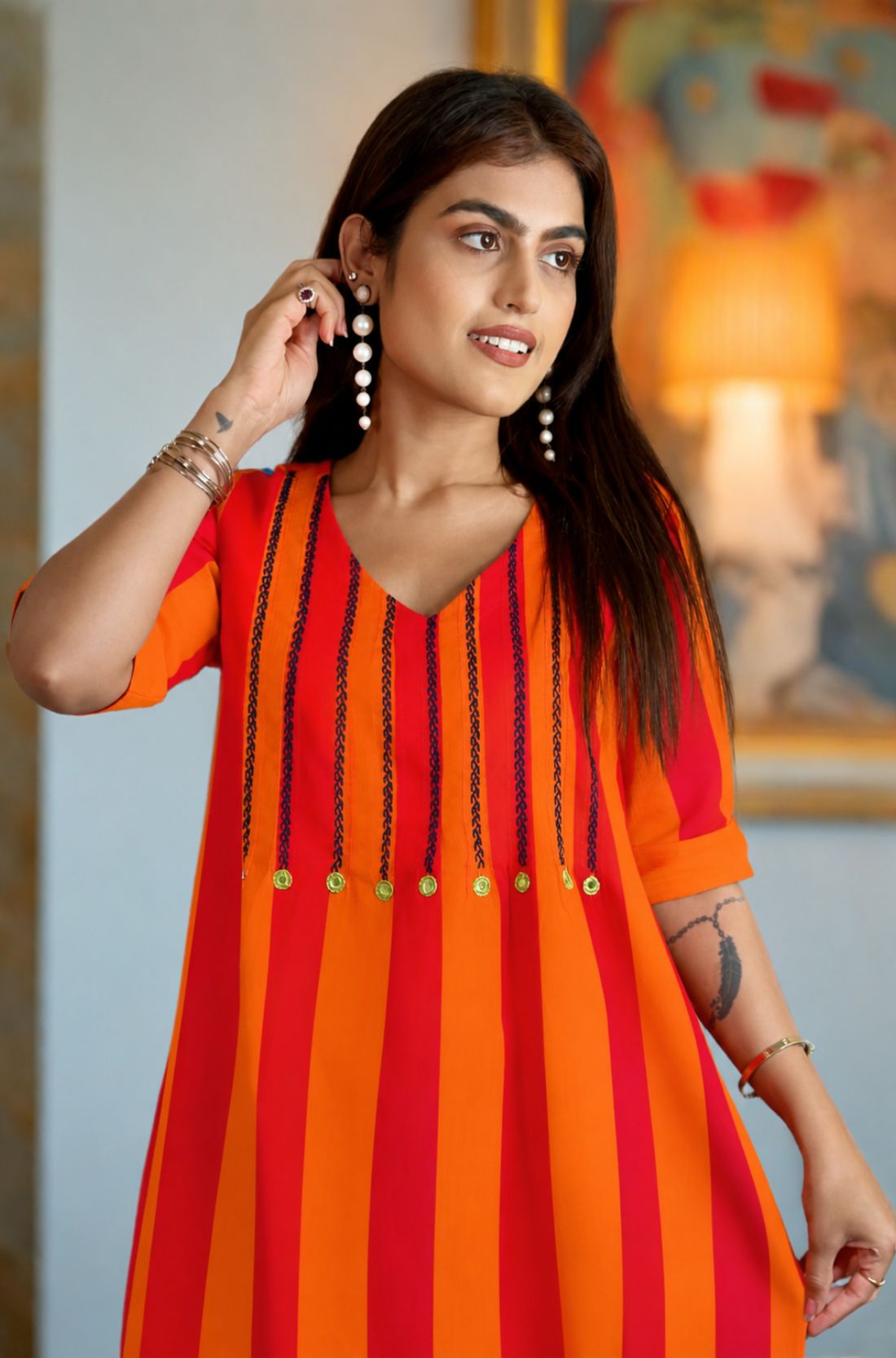 Close-up front view of the orange handloom cotton tunic featuring vertical black embroidery stitch work and yellow accent button detailing on the V-neck yoke.