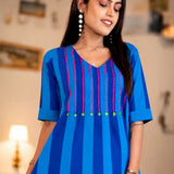 Close-up view of the V-neck yoke on the Philippine blue handloom cotton tunic, showing pink vertical embroidery and green accent buttons.