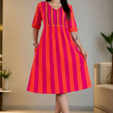 Model wearing a pure handloom cotton pintucks tunic dress in pink piano featuring vibrant pink and orange vertical stripes, a flare silhouette, and elbow-length cuffed sleeves.