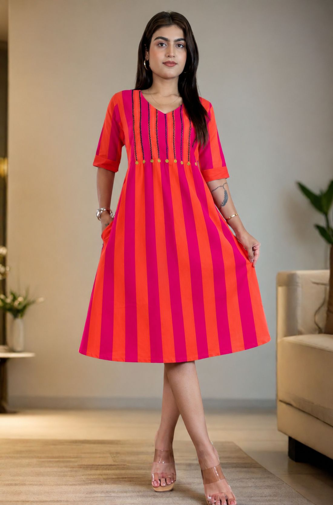 Model wearing a pure handloom cotton pintucks tunic dress in pink piano featuring vibrant pink and orange vertical stripes, a flare silhouette, and elbow-length cuffed sleeves.