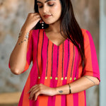 Close-up shot showing the V-neckline of the pink piano handloom cotton tunic with detailed vertical embroidery and bright accent buttons.