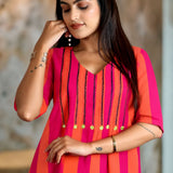 Close-up shot showing the V-neckline of the pink piano handloom cotton tunic with detailed vertical embroidery and bright accent buttons.