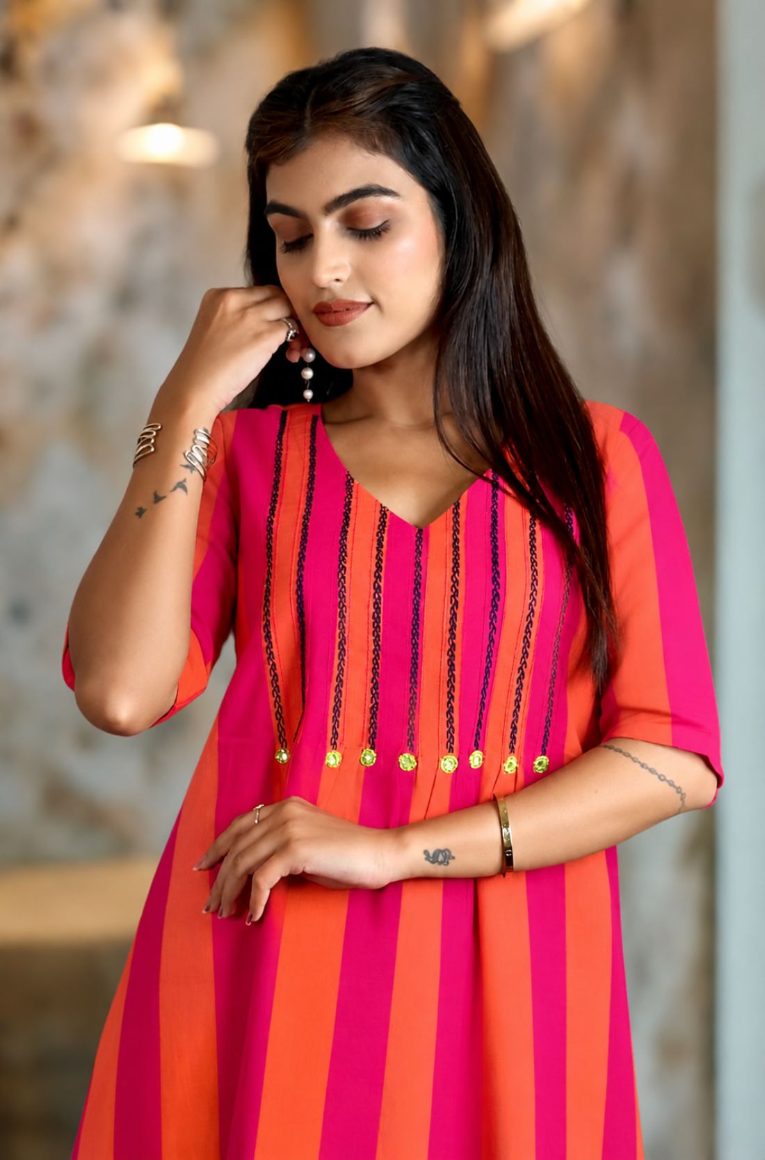 Close-up shot showing the V-neckline of the pink piano handloom cotton tunic with detailed vertical embroidery and bright accent buttons.