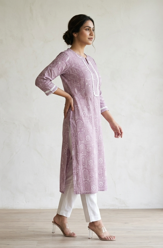 A woman standing sideways wearing a purple printed straight kurta and white pants, showcasing the garment fit.