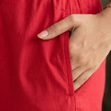 Close up utility view highlighting the convenient functional side pocket tailored into the matching printed trousers of the red pashmina silk kurta set, with a hand resting inside.