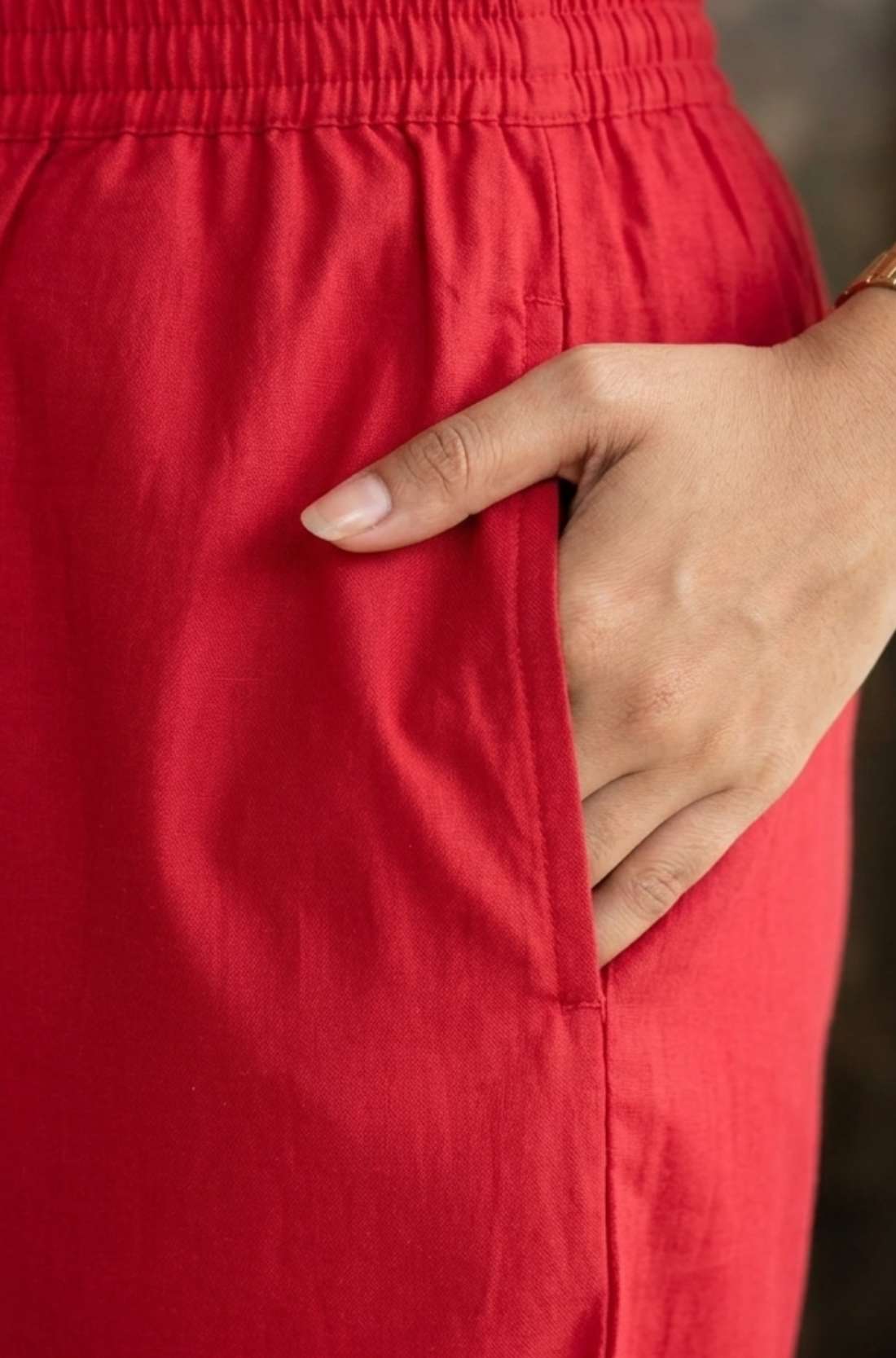 Close up utility view highlighting the convenient functional side pocket tailored into the matching printed trousers of the red pashmina silk kurta set, with a hand resting inside.