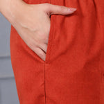 Close-up of rust orange cotton straight pants with elasticated waistband and side pocket, part of a women's embroidered kurta set.