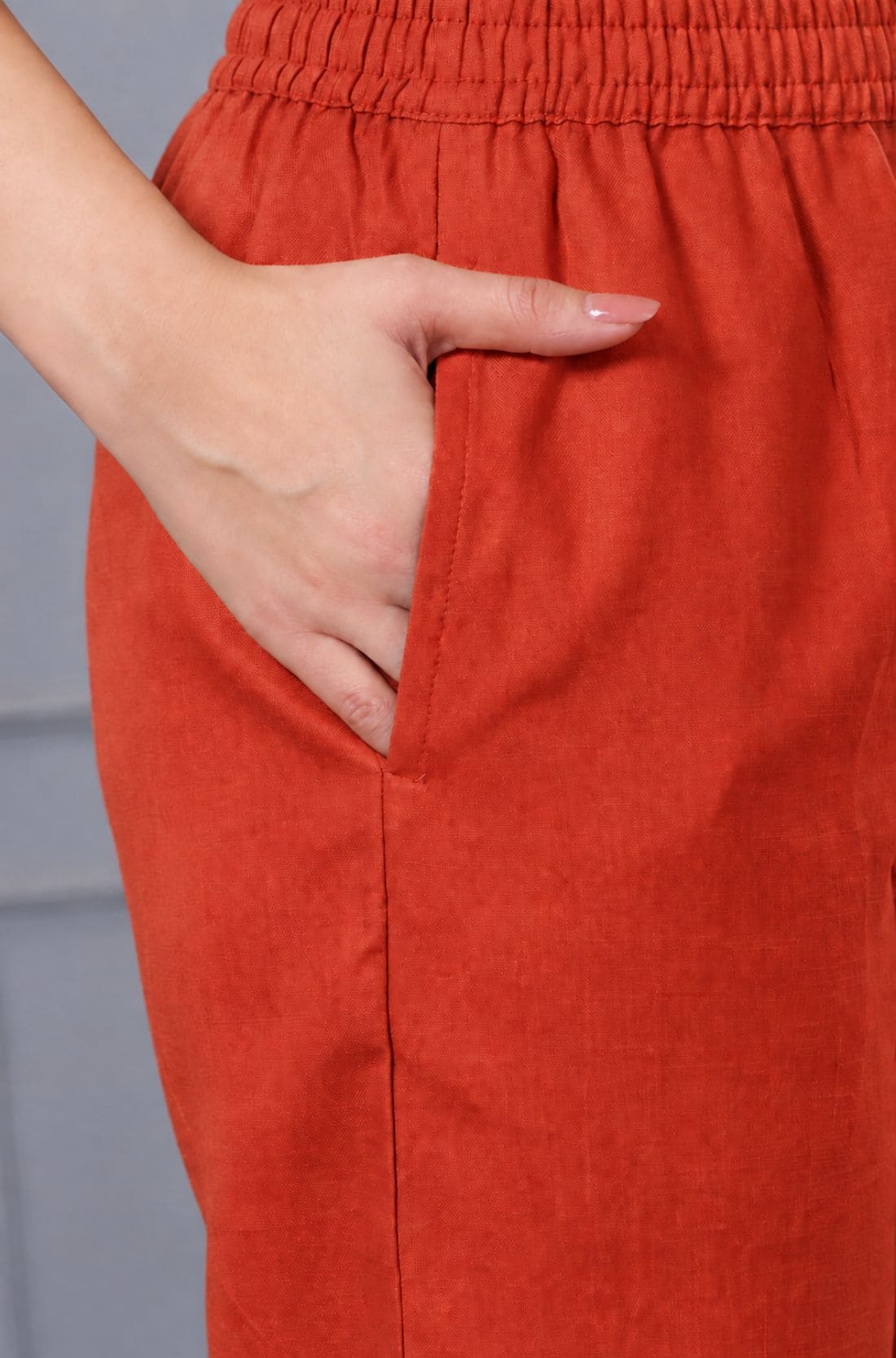 Close-up of rust orange cotton straight pants with elasticated waistband and side pocket, part of a women's embroidered kurta set.