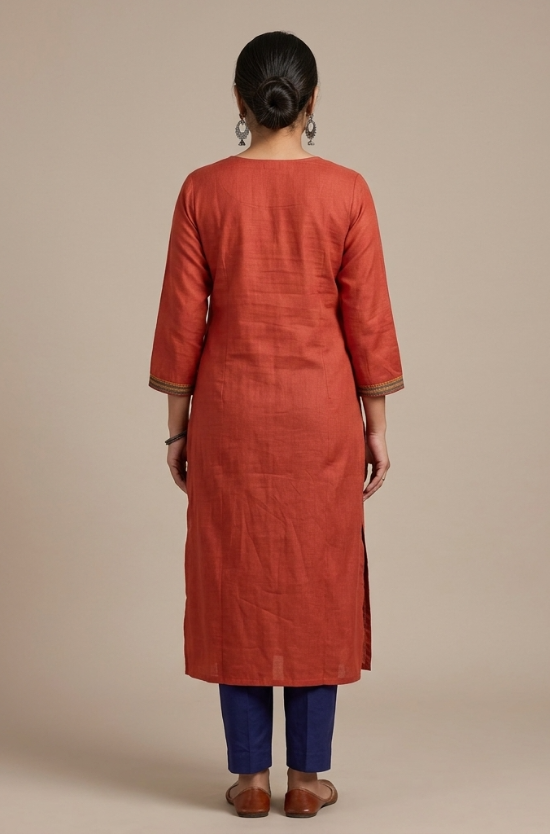 A full-length rear view of a woman modeling a rust-orange straight-cut kurta and blue pants.