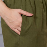 Close up view showcasing the practical side utility pocket seamlessly tailored into a sage green cotton floral print straight kurta, with a hand resting inside the pocket over matching straight trousers.