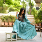 Model sitting in sea green aari embroidery flared kurti with contrast black yoke