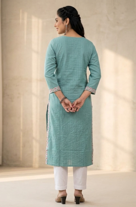 A rear view of a woman wearing a sea-green straight-cut kurta paired with white trousers.