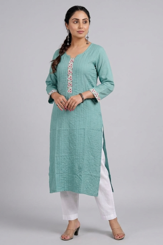 A full-length studio shot of a woman modeling a sea-green straight kurta with white pants. A woman posing with her hands near her face, wearing a sea-green embroidered kurta in a garden sea-green-kurta-walking-shot. A woman walking in a garden wearing a sea-green kurta, show casing the flow and drape of the fabric. sea-green-kurta-tea-lifestyle. A woman holding a clay cup while leaning against a wooden gate, dressed in a sea-green ethnic kurta.